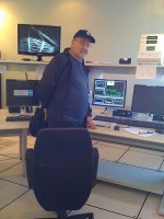 Dr. Massimo Tarenghi stands in the middle of the cerebral cortex of the 8.2 meter telescope (seen on the monitor above his right shoulder) as data on weather is presented on the screen in the middle.